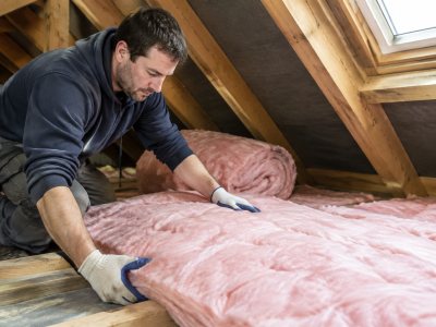 Handyman installing loft insulation in a home attic